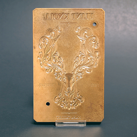 Sculpted brass emboss die of a stylized deer illustration, and type for a wine label